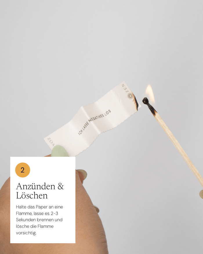 Zufriedenheits-Papier in Hand, mit brennender Zündholzflamme. Anleitung zum Verbrennen von Negativität.