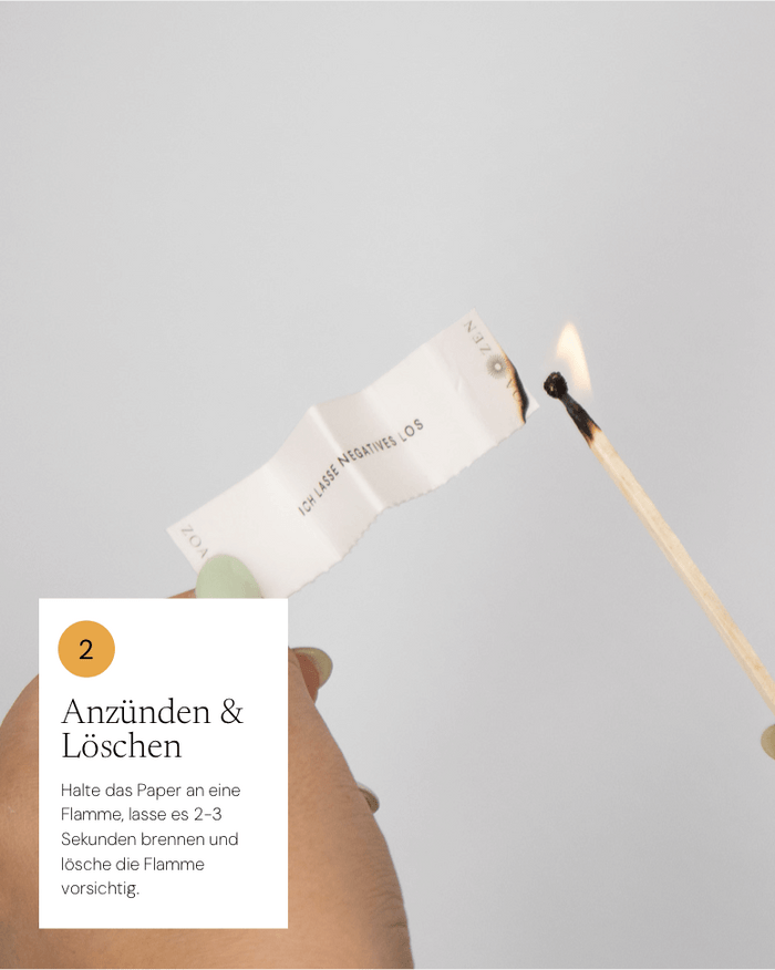 Anzünden und Löschen Anleitung: Papier wird angezündet, Hand hält einen Streichholz, neutraler Hintergrund.
